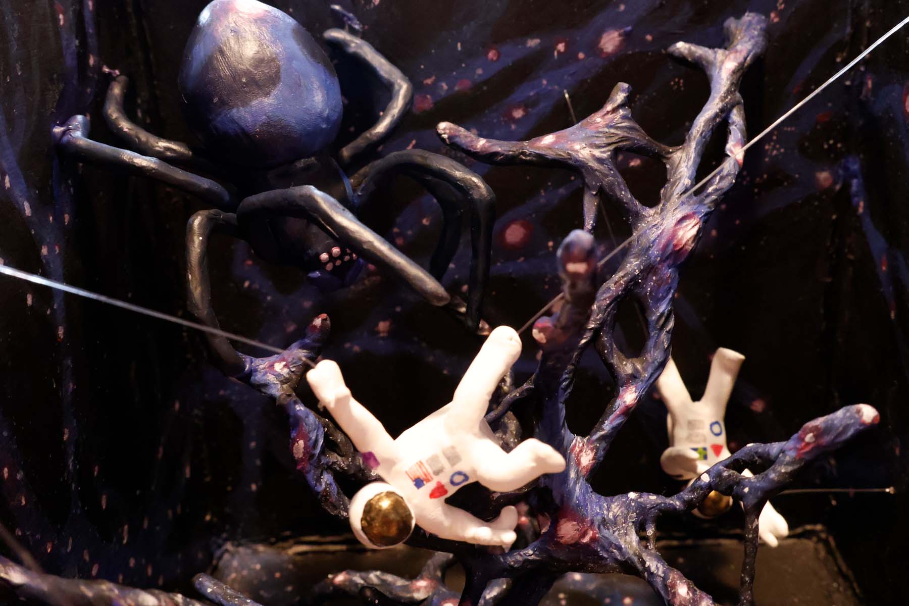 A closeup of the astronaut in the top left, who appears to be drifting dangerously close to the cosmic spider.