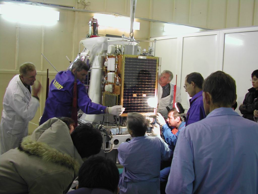 A dozen people attach STSAT-1 to a part of the launching mechanism.